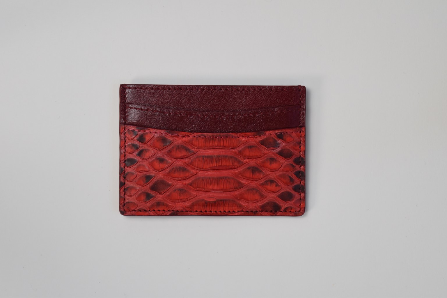 a red python skin card holder on a white surface