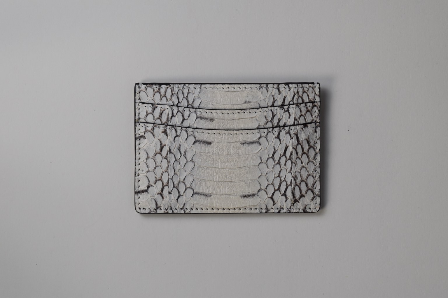 an alligator skin card holder on a white surface